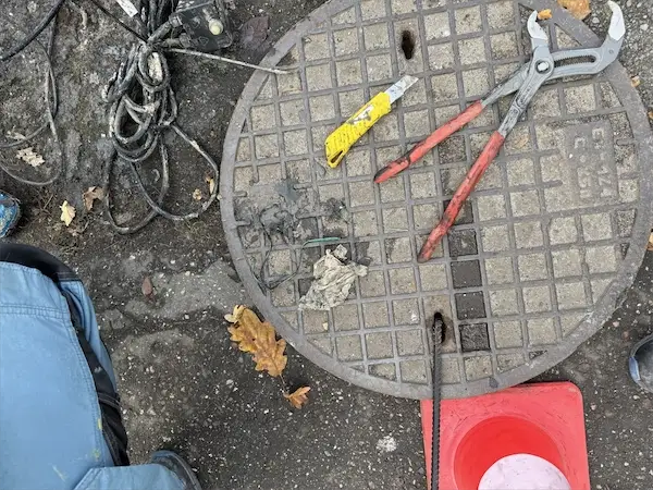Narzędzia hydrauliczne przy włazie kanalizacyjnym — pogotowie kanalizacyjne